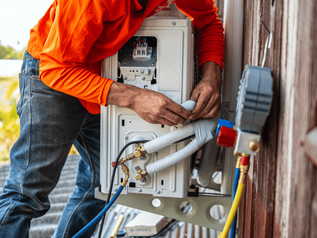 A-Comfort Service technician installing a new outdoor HVAC unit at a residential property.