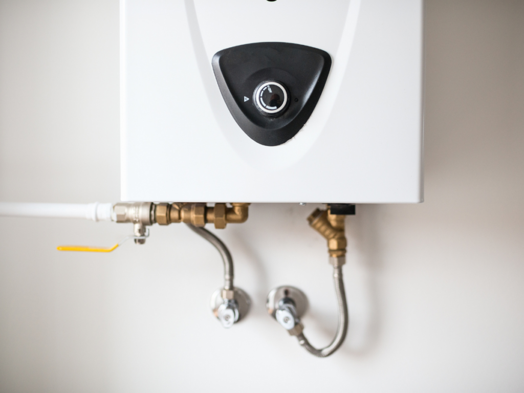 A compact, white wall-mounted water heater with professional plumbing connections and shut-off valves.