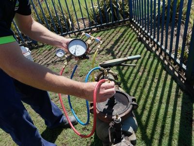 A-Comfort Service technician using a digital testing gauge to perform a certified backflow preventer inspection in Pittsburgh.